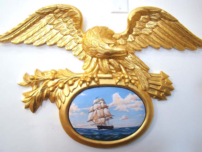 A Magnificent late 20th century Carved and Gilded American Eagle surmounting a painting of a ship at sea under full sail.